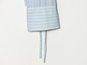 Détail de manchette de chemise à rayures bleues et blanches avec liens à nouer délicats