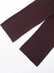 Dettaglio ravvicinato della trama del tessuto a costine bordeaux scuro di questi pantaloni