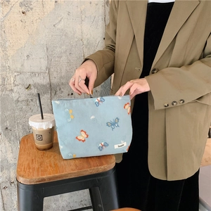 Detail view of the intricate butterfly embroidery on the light blue zipper cosmetic bag