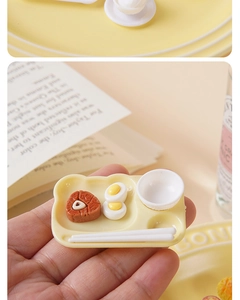 Miniature dollhouse food set with fried egg and steak on tray held by fingers