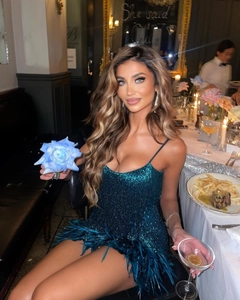 Robe chic à paillettes avec bordure en plumes bleu paon, portée dans un dîner élégant