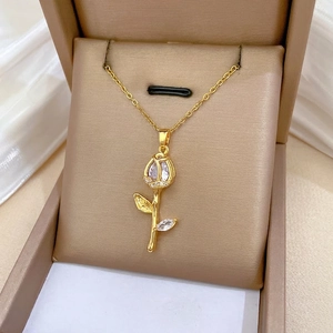 Elegant gold tulip pendant necklace with sparkling cubic zirconia on champagne velvet
