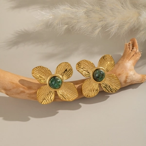 Détail de boucles d'oreilles fleur dorées vintage avec turquoise verte sur une branche