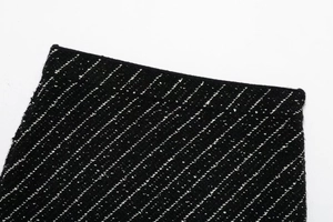 Close-up of black and white tweed knit fabric texture showing premium weaving detail