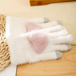 Detail of white plush gloves with pink heart decor and grey touch screen fingertips