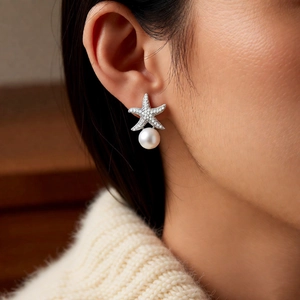 Detailed view of starfish pearl earrings with sparkling crystals worn by a model