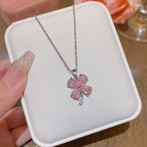 Collier avec pendentif trèfle rose et chaîne argentée sur coussin à bijoux