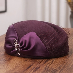 Detail of wool pillbox hat with mesh veil, satin bow, and rhinestone brooch