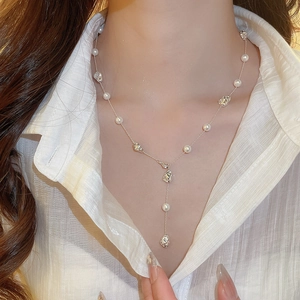 Macro shot of silver Y-shaped necklace with pearls and irregular metallic beads on neck