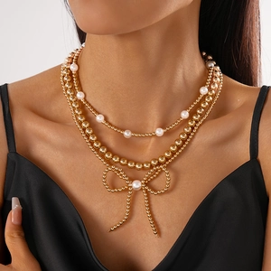 Detailed view of triple-layered gold bead necklace featuring a pearl bow pendant for women