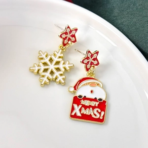 Detail of asymmetric Christmas earrings with Santa and snowflake on a ceramic plate