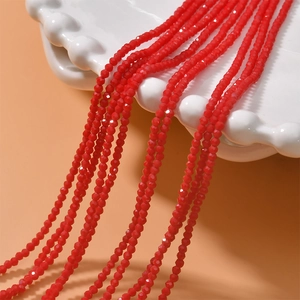 Macro shot of 2mm faceted red crystal beads on a white scalloped ceramic plate