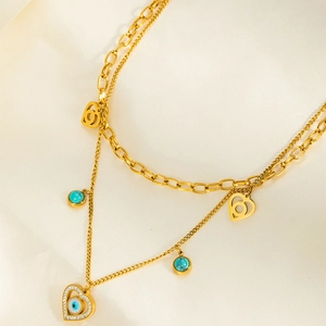 Détail du collier double en acier doré avec pendentifs cœur et œil bleu turquoise