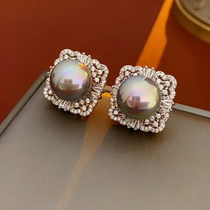 Macro shot of vintage silver earrings featuring dark pearls and square zircon frames