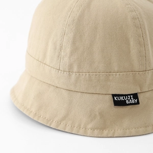 Detail showing beige cotton baby sun hat with KUKUJI BABY label and soft fabric texture