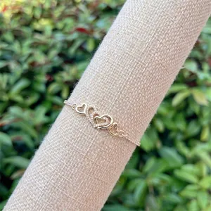 Close-up of interlocking gold heart charms with pavé cubic zirconia on a link bracelet