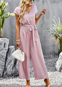 Pink V-neck short sleeve wide leg jumpsuit with waist belt shown in an outdoor setting