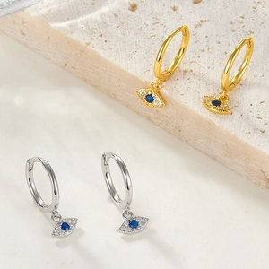 Detailed view of silver and gold evil eye hoop earrings with blue stones and zircons