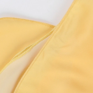 Detailed macro shot of premium stitching on high-quality yellow fabric dress