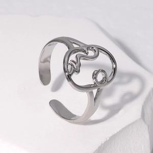 Detailed view of silver abstract face hollow ring on a white textured rock background