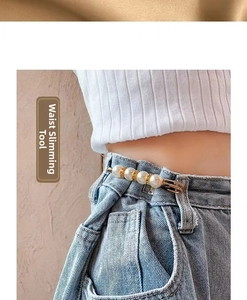 Close-up of pearl geometric brooch pin used for waist adjustment on denim jeans