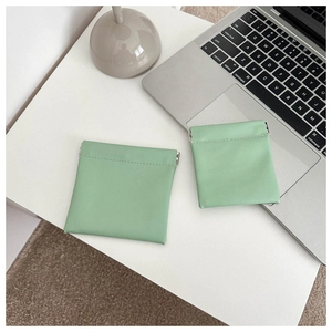 Close-up of mint green faux leather coin pouches with metal spring closure on a white desk