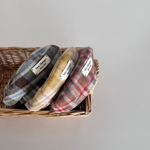 Detailed close-up of three plaid wool berets for kids in a vintage woven basket