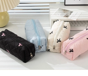 Close-up of four floral quilted pencil cases in black, blue, beige and pink colors