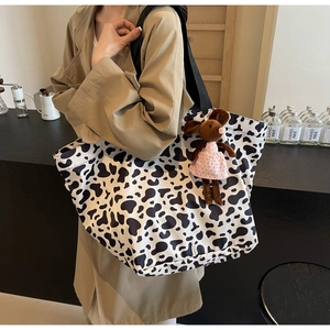 Dettaglio borsa tote in tela con stampa mucca e ciondolo a forma di topo sulla spalla