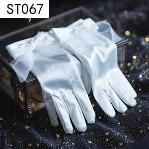Detailed view of white satin bridal gloves featuring a large bow on a vintage glass box