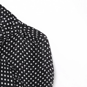 Polka dot chiffon cape shirt with bow detail featuring black and white pattern design
