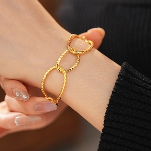 Macro shot of gold plated chunky chain bracelet featuring textured oval link details