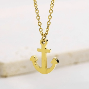 Polished gold anchor pendant necklace for men and women on white marble background