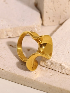 Macro shot of 14K gold-plated S-shaped wavy ring on a textured stone surface