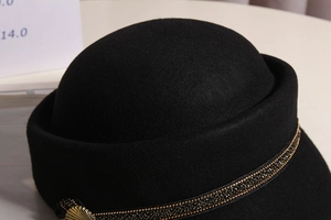 Detailed close-up of wool fedora with gold-beaded ribbon and vintage fan buckle