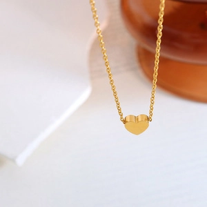 Vue macro d'un pendentif cœur en or poli sur un collier minimaliste à maille O