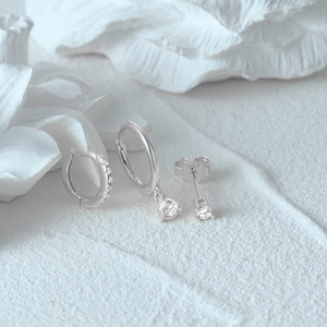 Detail of 925 sterling silver earring set with cubic zirconia on textured background