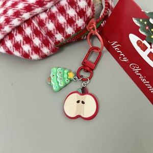 Detail showing a Christmas tree and red apple keychain pendant with a red metal ring