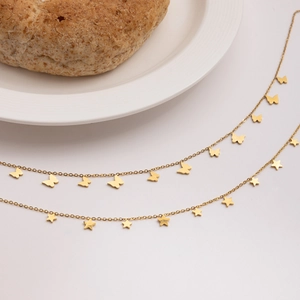 Detailed view of 18K gold star and butterfly pendants on delicate stainless steel chains