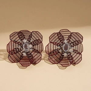 Detail of vintage burgundy hollow flower earrings with white zircon accents and shadows