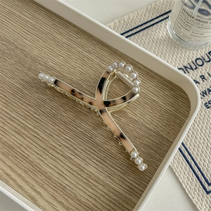 Detail of leopard print acetate hair claw clip with pearls and golden metal finish