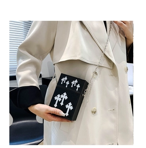 Detail of black crossbody phone bag featuring white gothic cross appliques and silver chain