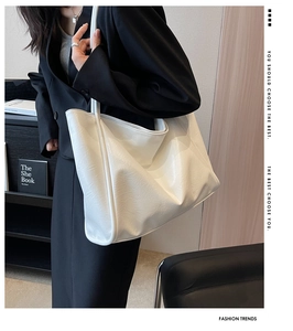 Vue détaillée d'un grand sac cabas blanc en cuir souple porté avec un blazer noir chic