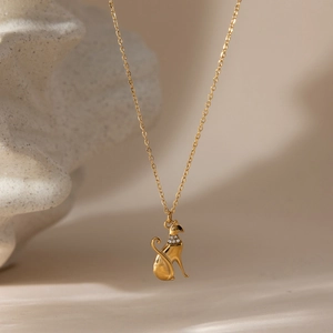 Detailed view of a gold cat pendant with a sparkling zircon collar on a fine chain