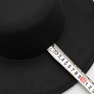 Detailed view showing the 7cm wide brim of a black wool felt boater hat with measuring tape