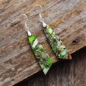 Detail view of teardrop imperial stone earrings on a rustic wood background