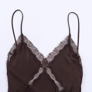 Détail d'un caraco en satin marron avec une bordure en dentelle cil sur le décolleté