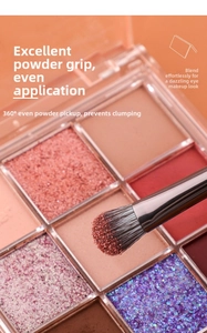 Macro detail of eye shadow brush picking up shimmer powder from a warm palette