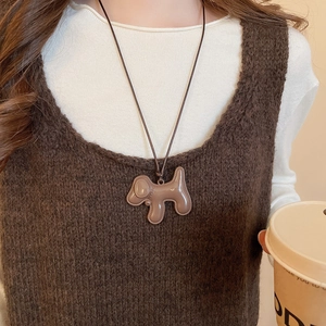 Gros plan d'un collier pendentif chiot marron porté sur un pull marron assorti