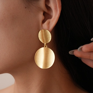 Detailed view of gold geometric layered disc earrings with brushed metallic texture
